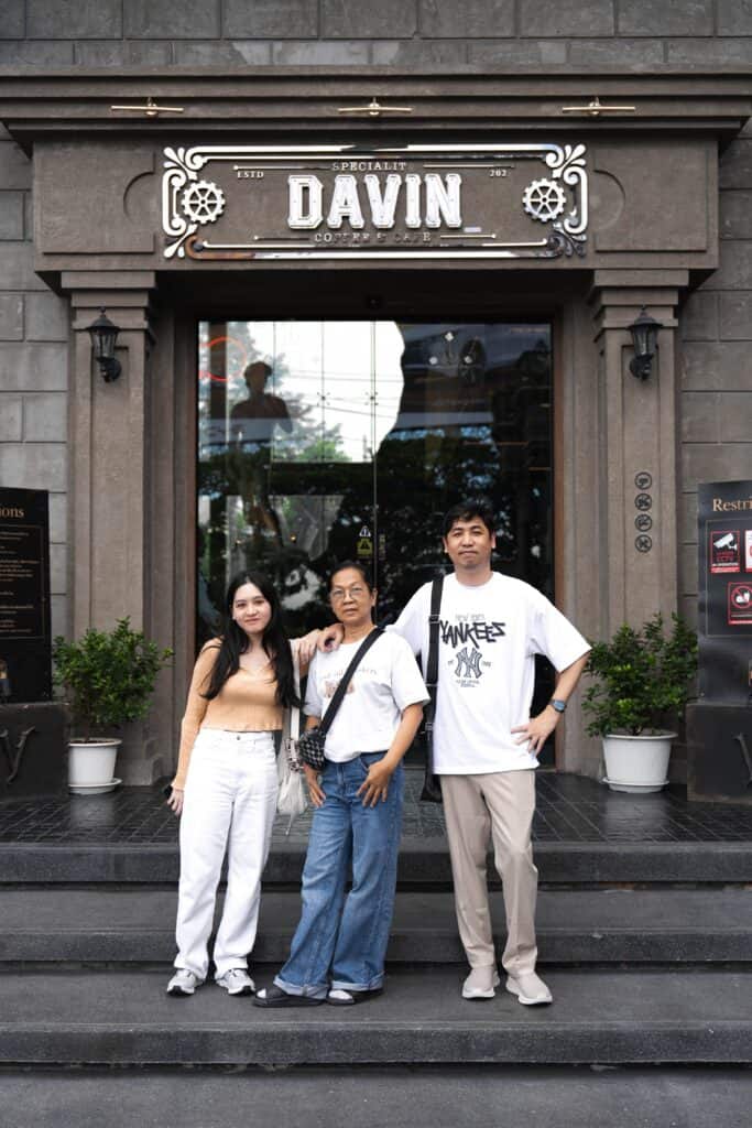 A family of three posing for a portrait photo in front of the main entrance of Davin Cafe.