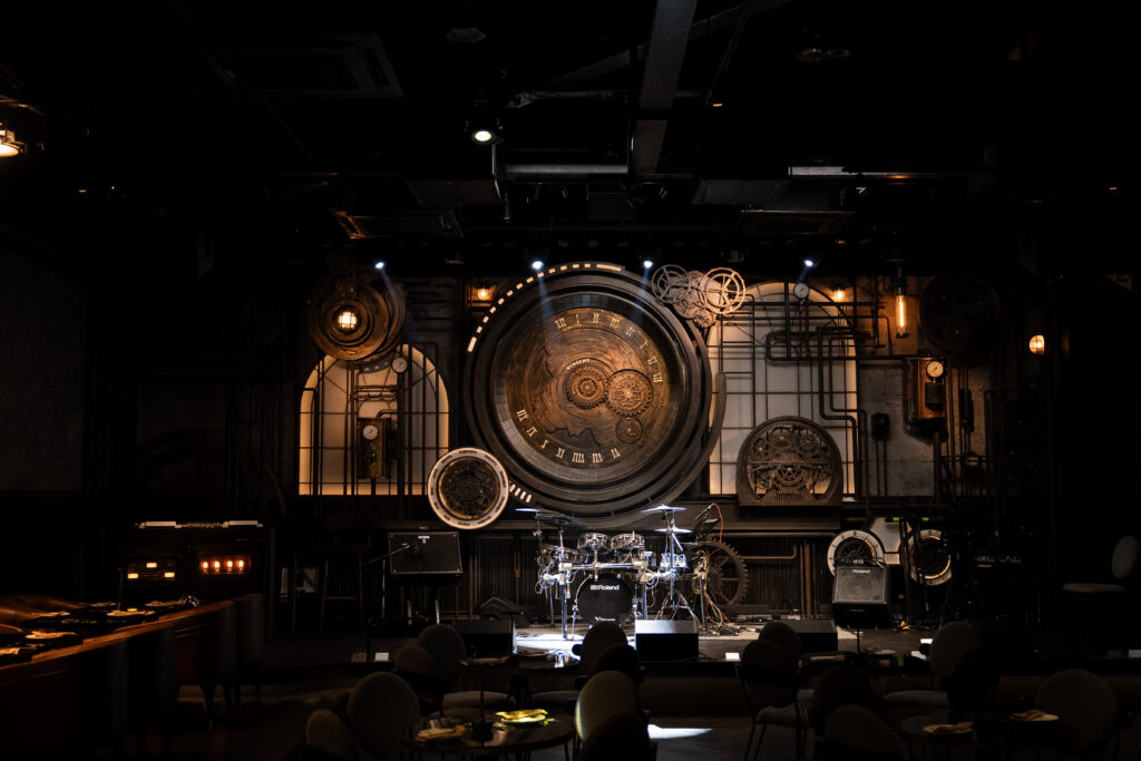 Steampunk-inspired live music stage inside a luxury cocktail bar and event venue in Bangkok, featuring dramatic industrial design and an immersive nightlife atmosphere for concerts and private events