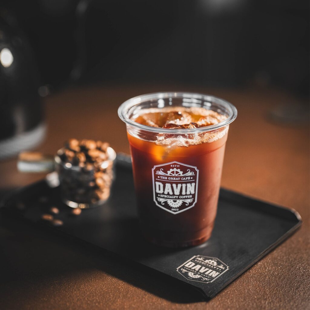 อเมริกาโน่เย็นจาก DAVIN CAFE เมนูกาแฟสกัดร้อนแล้วเติมน้ำและน้ำแข็ง ใช้ประกอบบทความเปรียบเทียบความแตกต่างระหว่าง Cold Brew กับ Americano ในด้านรสชาติ ความเข้มข้น กลิ่นกาแฟ และวิธีการสกัด