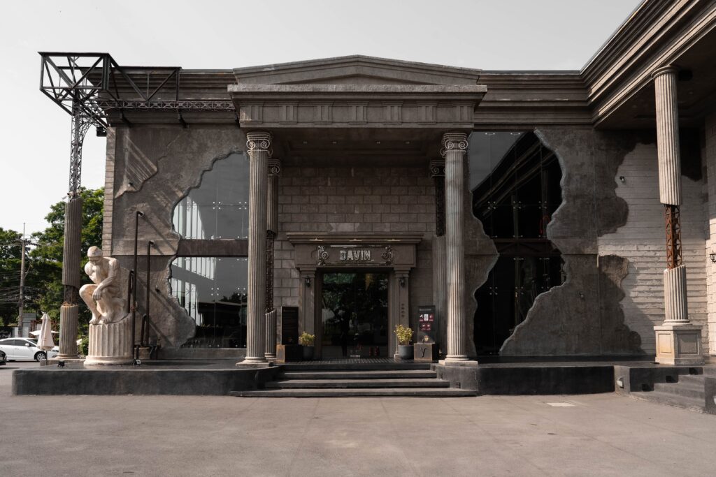 Exterior view of Davin Cafe, a European-style cafe in Bangkok featuring Roman-inspired columns, classical sculpture, and grand architectural details that create a destination cafe experience before guests step inside.