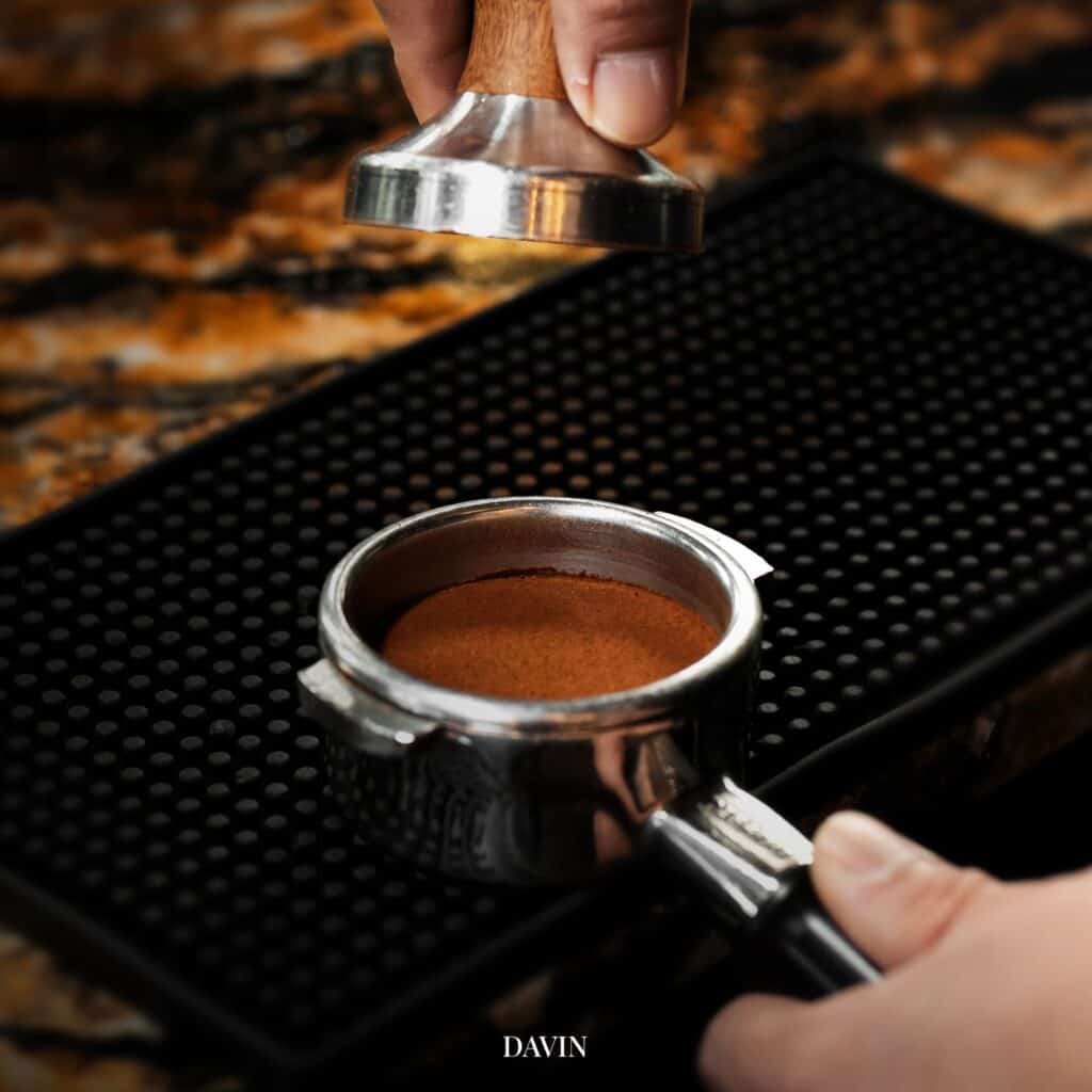 ขั้นตอนการแทมป์ผงกาแฟในพอร์ตาฟิลเตอร์ของ Davin Cafe ก่อนสกัดเอสเปรสโซ่ สะท้อนความพิถีพิถันของกาแฟ เข้มที่ต้องอาศัยการบด การกด และการควบคุมรสชาติอย่างแม่นยำ เพื่อให้ได้กลิ่นหอมชัด บอดี้แน่น และคาแรกเตอร์กาแฟที่ลึกกว่าการชงทั่วไป