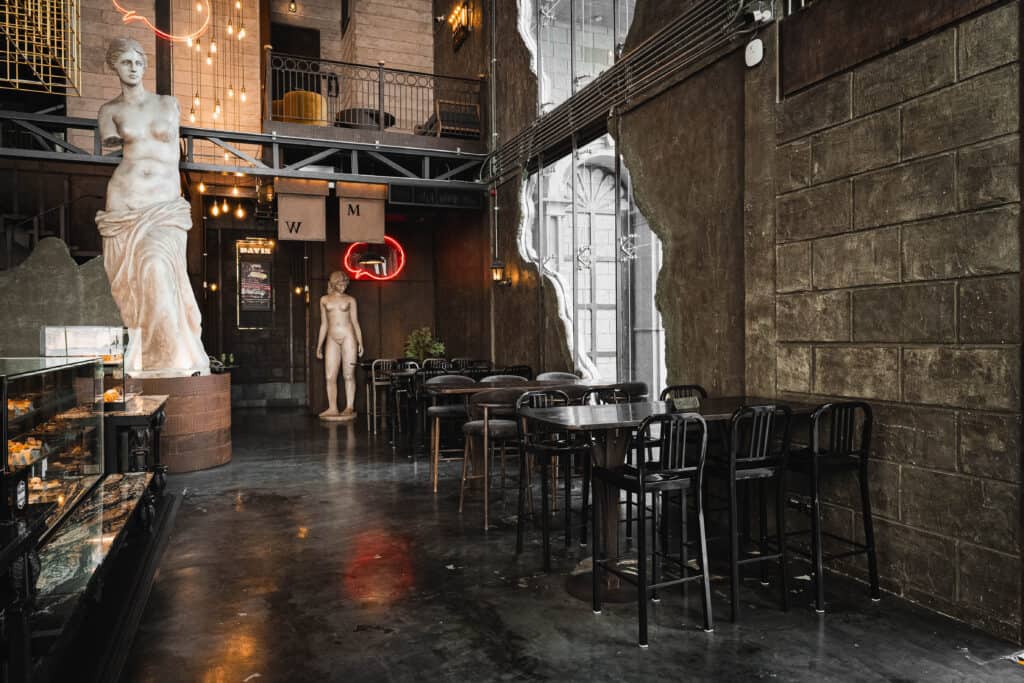Quiet seating area inside Davin Cafe in Ramintra, featuring high ceilings, natural light, European-inspired decor, and well-spaced tables for guests looking for a work-friendly cafe with a calm atmosphere and comfortable focus time.